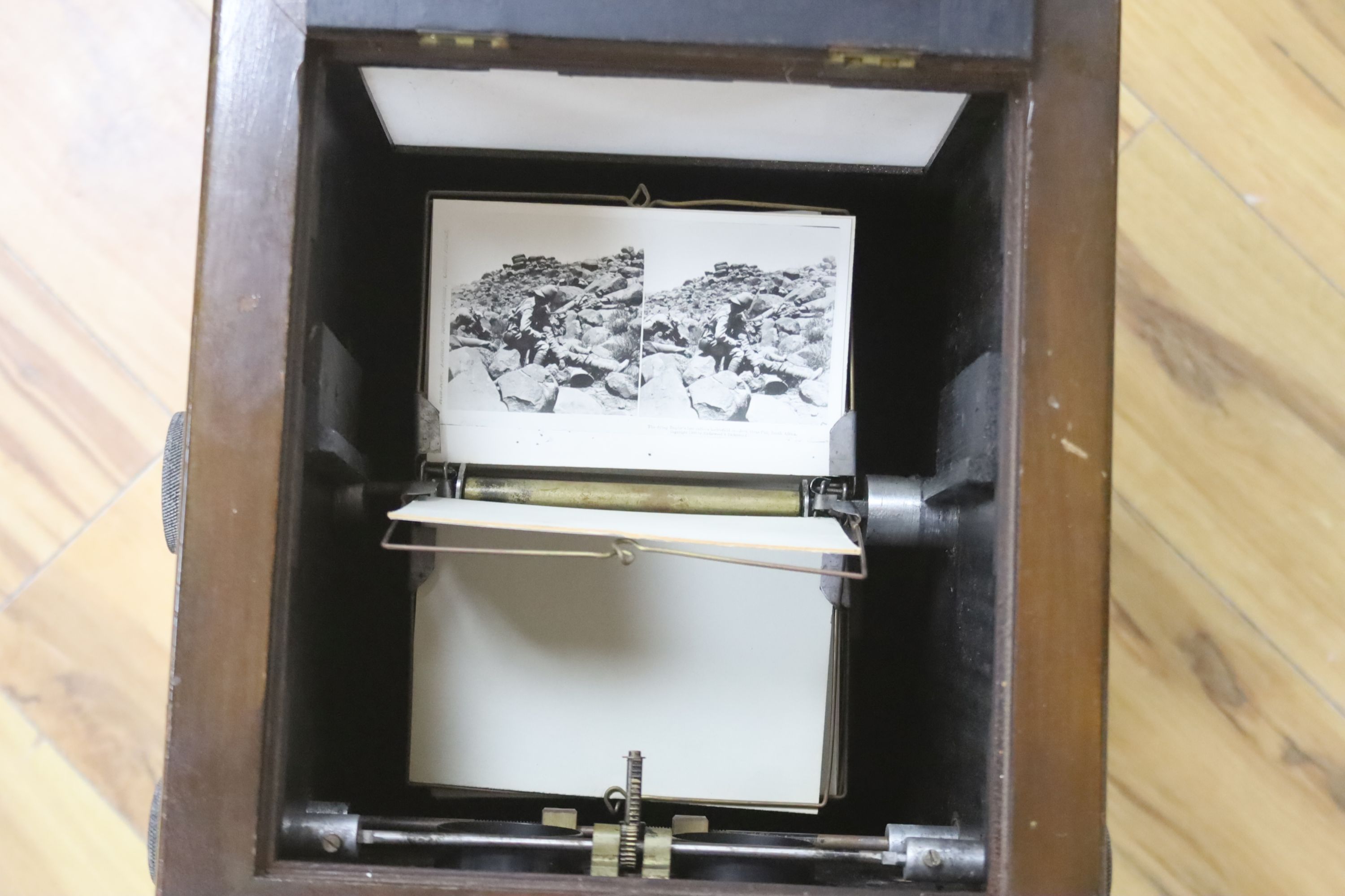 An early 20th century mahogany table top stereoscopic card viewer with monochrome Boer War cards, height 53cm